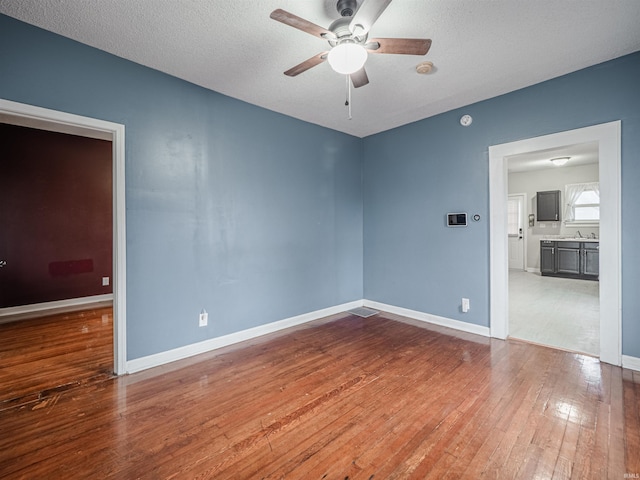 unfurnished room with ceiling fan, hardwood / wood-style floors, a textured ceiling, and sink