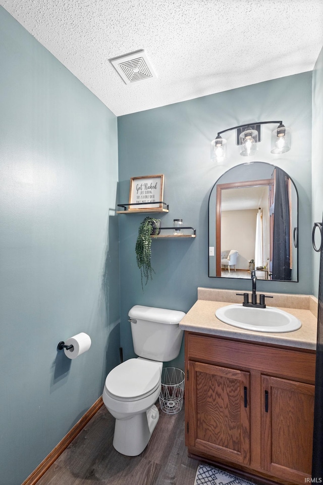 bathroom featuring hardwood / wood-style flooring, vanity, toilet, and a textured ceiling