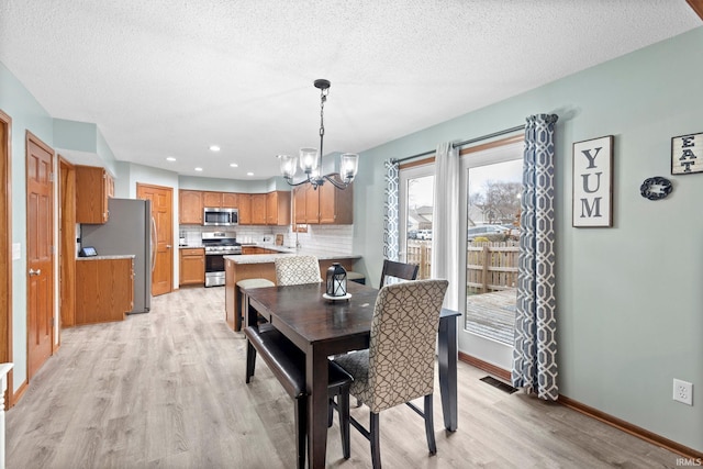 dining area with a chandelier, a textured ceiling, and light wood-type flooring