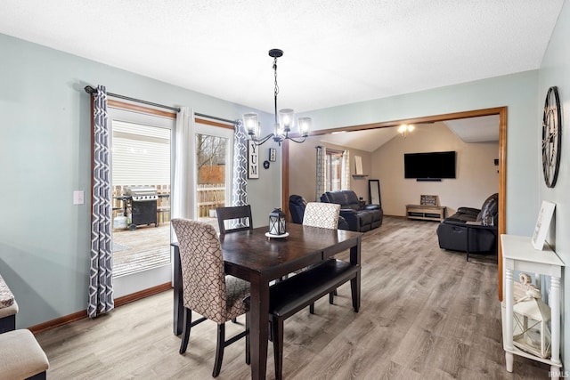 dining room featuring light wood-type flooring, vaulted ceiling, and an inviting chandelier