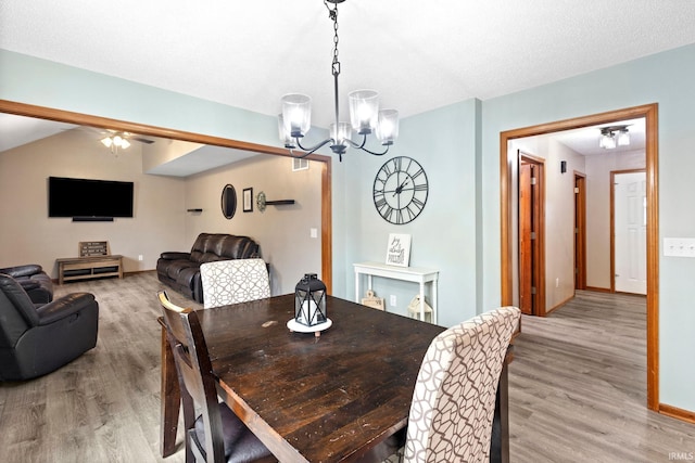 dining area with light hardwood / wood-style flooring and ceiling fan with notable chandelier