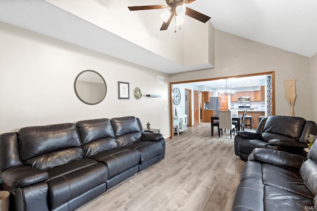 living room with ceiling fan with notable chandelier, light hardwood / wood-style floors, and lofted ceiling