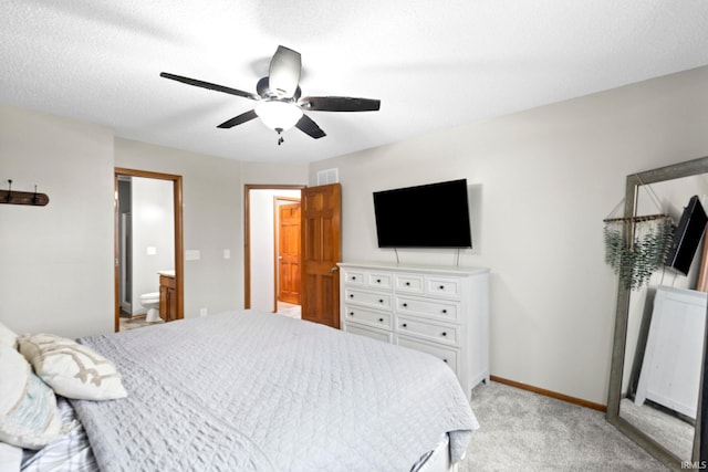 bedroom with ceiling fan, light colored carpet, and ensuite bath