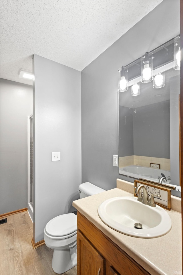 bathroom featuring vanity, a textured ceiling, hardwood / wood-style flooring, and a shower with door