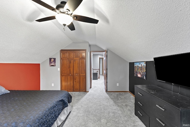 bedroom featuring light carpet, vaulted ceiling, ceiling fan, a textured ceiling, and a closet