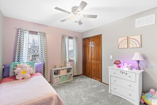 carpeted bedroom featuring multiple windows, ceiling fan, and a closet