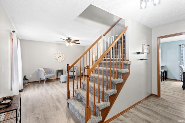 stairway with hardwood / wood-style flooring and ceiling fan