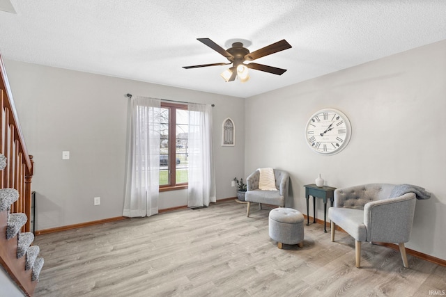 living area with ceiling fan, light hardwood / wood-style floors, and a textured ceiling