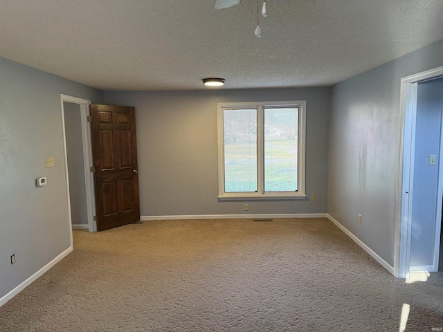 carpeted empty room featuring ceiling fan and a textured ceiling