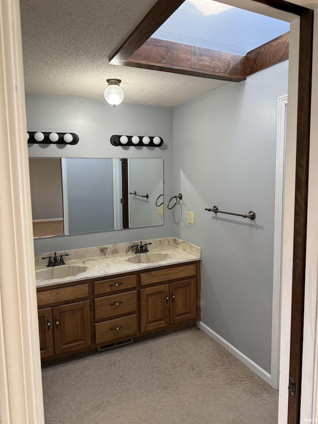 bathroom with vanity, a textured ceiling, and a skylight