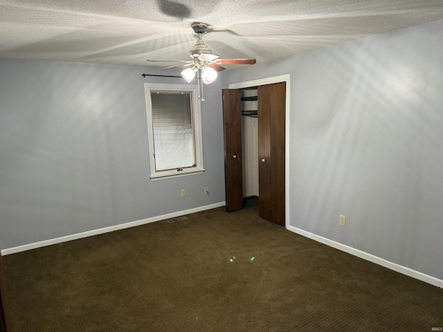 empty room featuring ceiling fan, dark carpet, and a textured ceiling