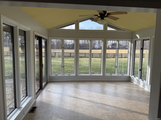 unfurnished sunroom featuring a rural view, vaulted ceiling, and ceiling fan