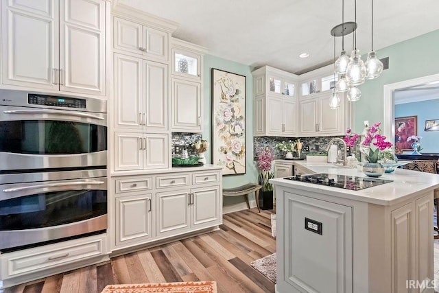 kitchen with white cabinetry, tasteful backsplash, double oven, decorative light fixtures, and black electric cooktop