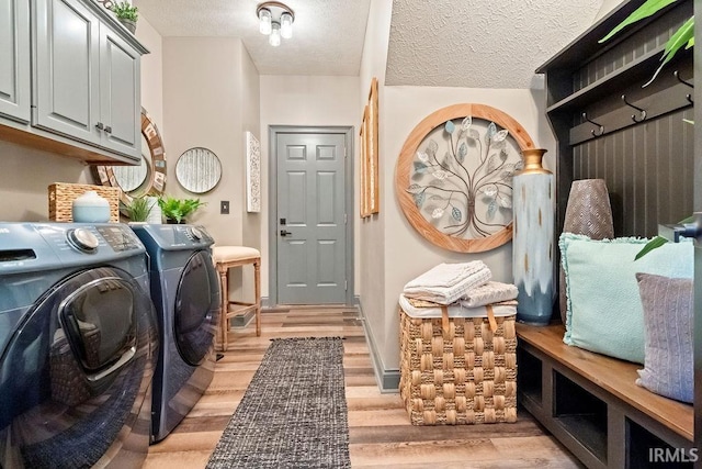 laundry area featuring washer and clothes dryer, a textured ceiling, and light wood-type flooring