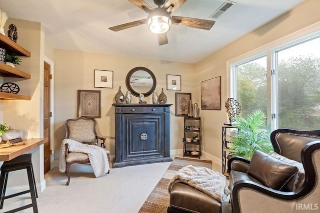 living area with light carpet and ceiling fan