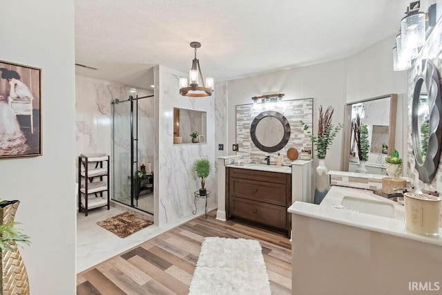 bathroom with an enclosed shower, vanity, a textured ceiling, wood-type flooring, and a chandelier