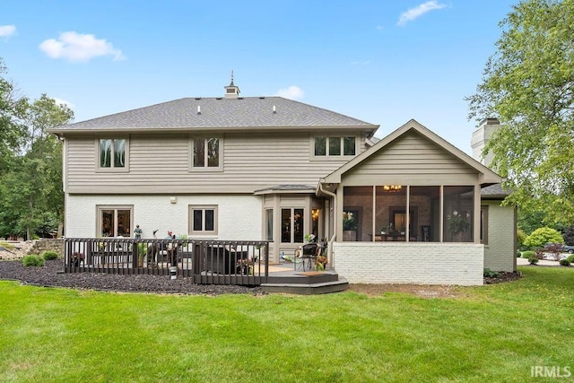 back of property with a wooden deck, a sunroom, and a yard