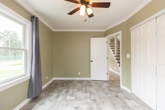 unfurnished bedroom featuring multiple windows, ceiling fan, and ornamental molding