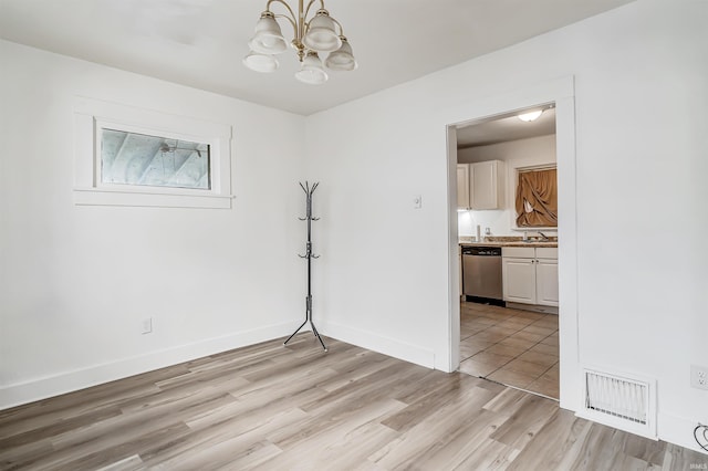 empty room with an inviting chandelier, light hardwood / wood-style flooring, and sink