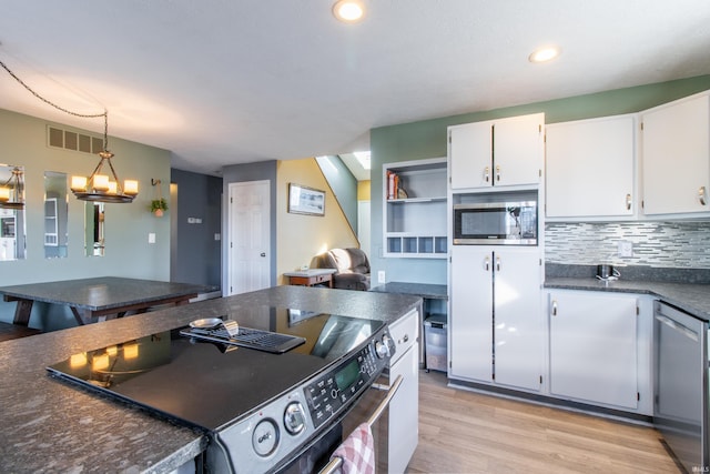 kitchen with white cabinetry, stainless steel appliances, a notable chandelier, backsplash, and light wood-type flooring