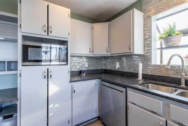 kitchen featuring white cabinetry, sink, dark stone counters, a textured ceiling, and appliances with stainless steel finishes