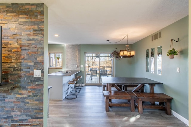 dining space featuring wood-type flooring and an inviting chandelier