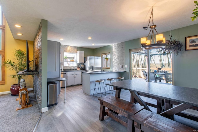 dining space featuring light wood-type flooring, sink, and a chandelier