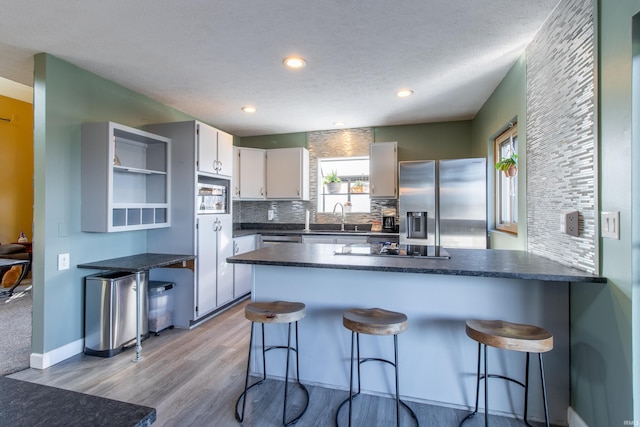 kitchen with appliances with stainless steel finishes, a textured ceiling, white cabinetry, and sink