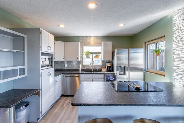 kitchen with a breakfast bar, white cabinetry, sink, and appliances with stainless steel finishes