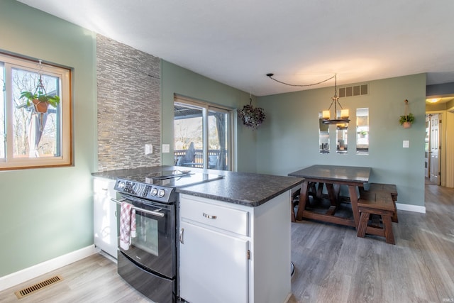 kitchen featuring electric range, light hardwood / wood-style flooring, kitchen peninsula, pendant lighting, and white cabinets