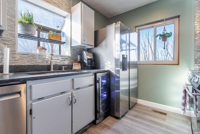 kitchen featuring sink, wine cooler, stainless steel dishwasher, backsplash, and white cabinets