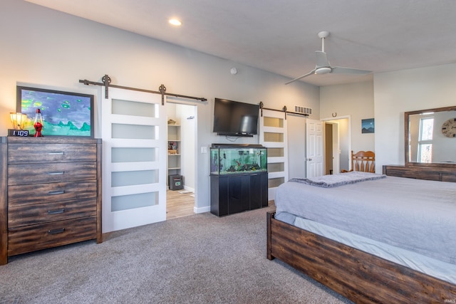 carpeted bedroom featuring a barn door and ceiling fan