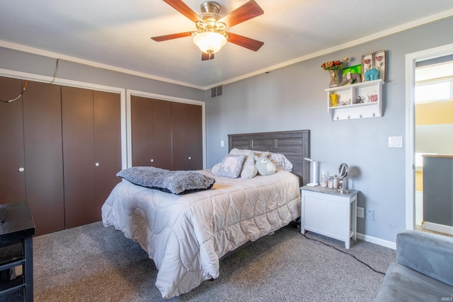 carpeted bedroom featuring multiple closets, ceiling fan, and crown molding