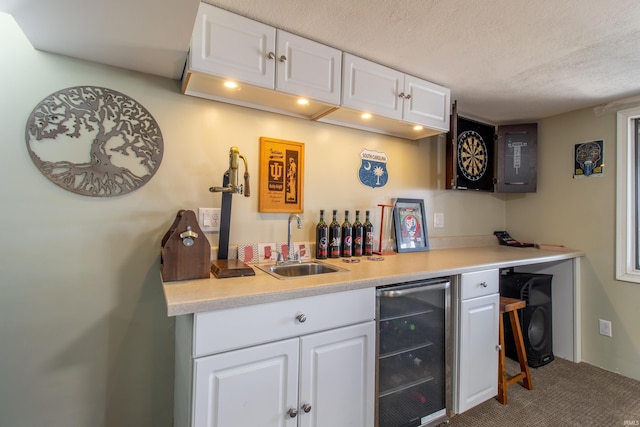 bar with white cabinets, sink, wine cooler, carpet flooring, and a textured ceiling