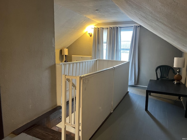 additional living space featuring lofted ceiling, hardwood / wood-style floors, and a textured ceiling