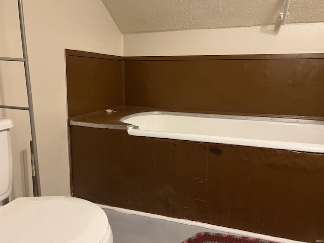 bathroom featuring toilet, lofted ceiling, and a textured ceiling