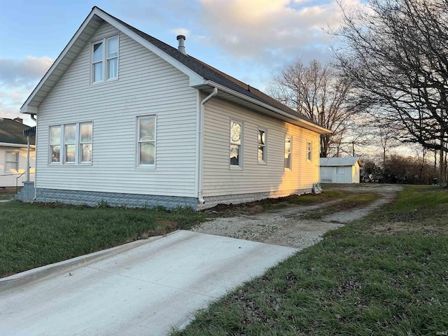 property exterior at dusk featuring a lawn