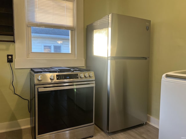 kitchen with light wood-type flooring, stainless steel appliances, and washer / clothes dryer