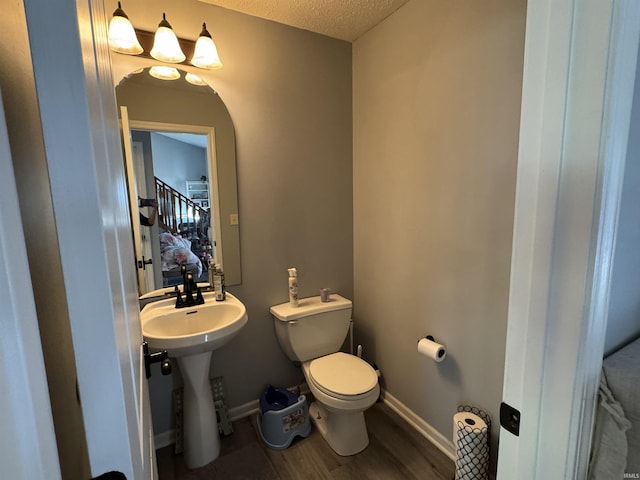 bathroom with hardwood / wood-style floors, a textured ceiling, toilet, and sink