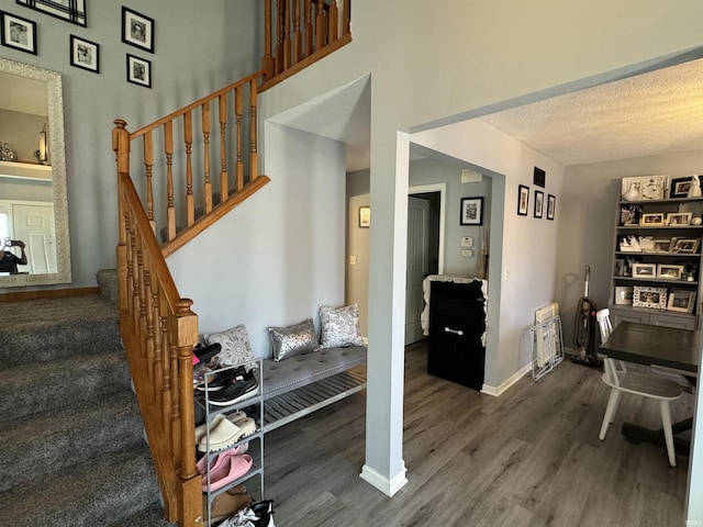 stairway with wood-type flooring and a textured ceiling