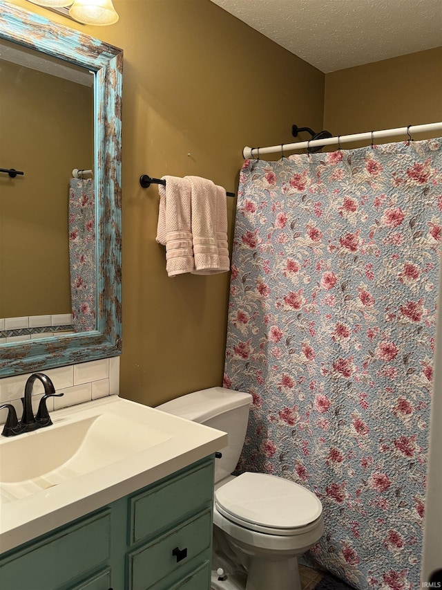 bathroom featuring vanity, toilet, a textured ceiling, and tasteful backsplash