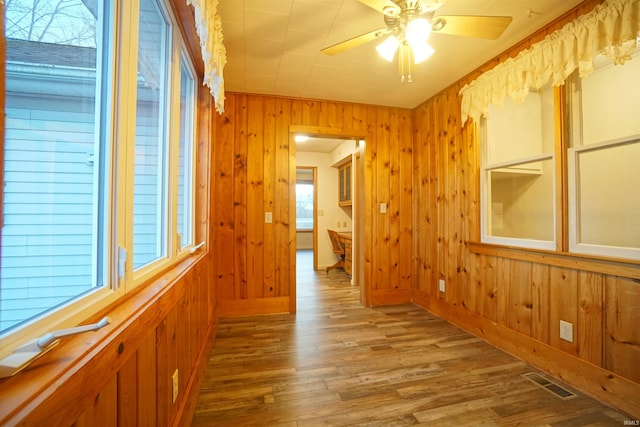 empty room featuring wooden walls, hardwood / wood-style floors, and ceiling fan