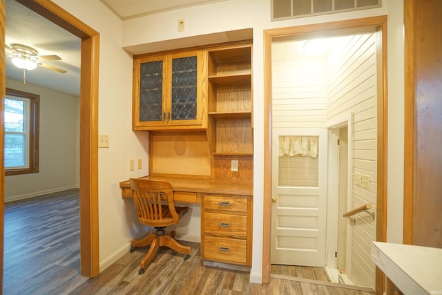 office space with ceiling fan, built in desk, and dark wood-type flooring