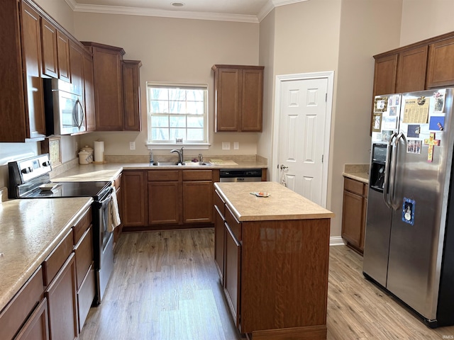 kitchen featuring appliances with stainless steel finishes, light hardwood / wood-style floors, a kitchen island, and sink