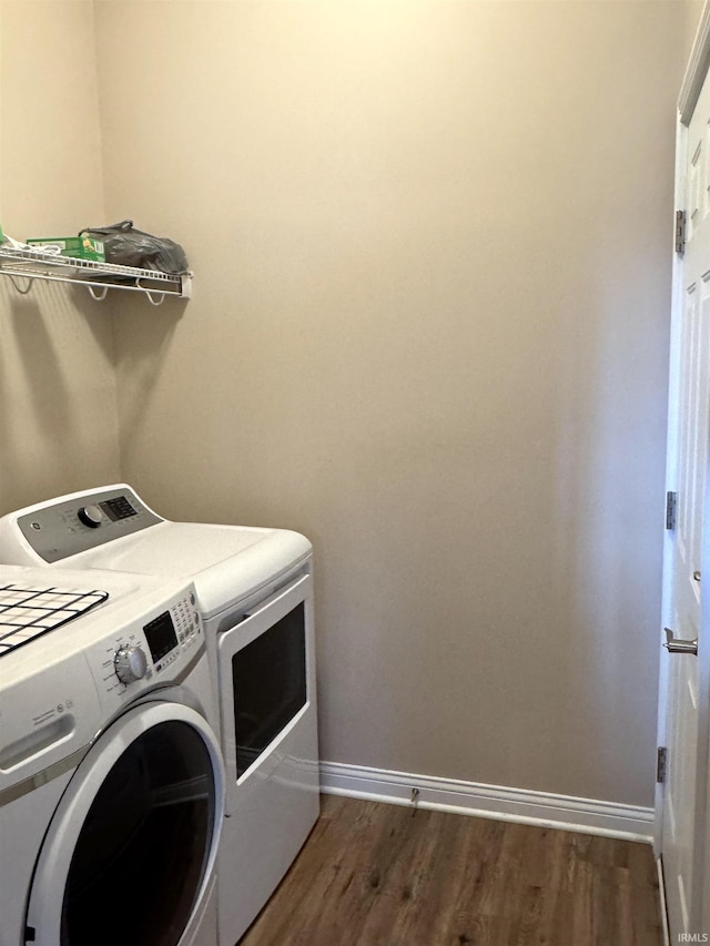 washroom with dark hardwood / wood-style flooring and washing machine and dryer