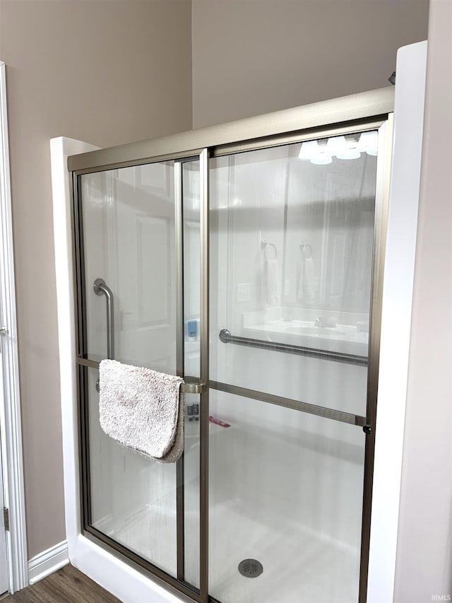 bathroom with hardwood / wood-style flooring and an enclosed shower