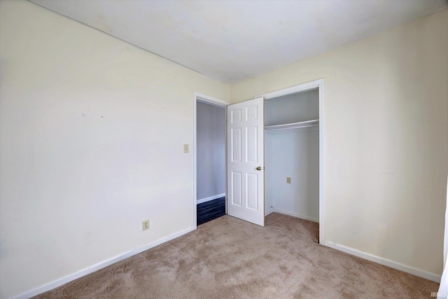 unfurnished bedroom with light carpet and a closet