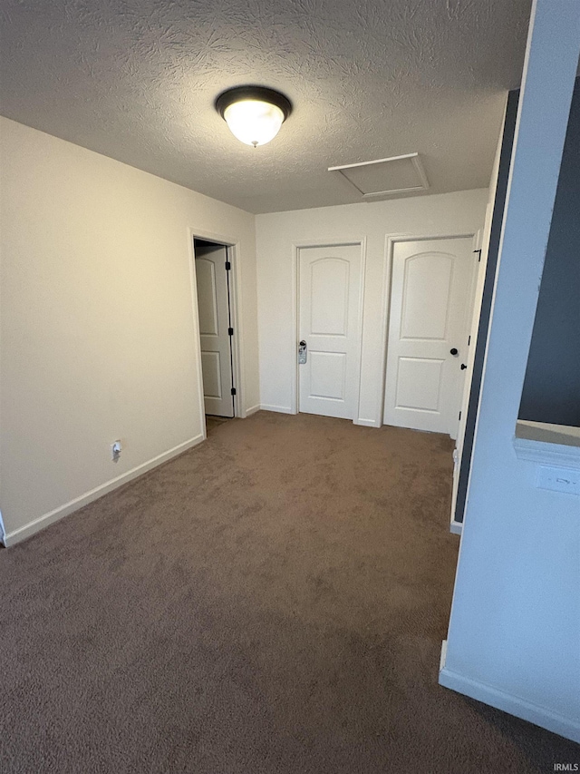 empty room featuring a textured ceiling and dark colored carpet