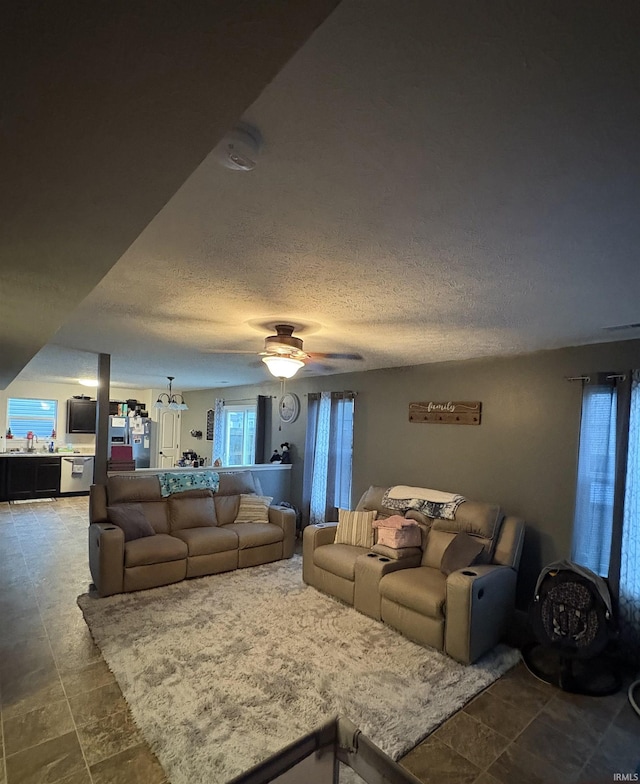 living room featuring ceiling fan, sink, and a textured ceiling