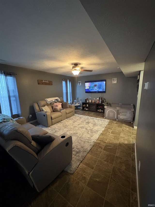 living room featuring ceiling fan and a textured ceiling